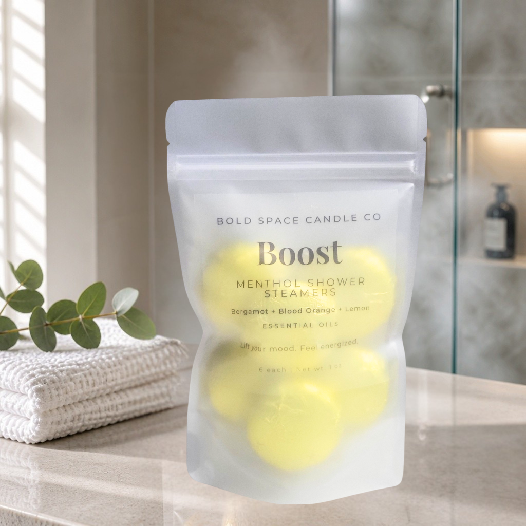 A stand-up pouch of Bold Space Candle Co. Boost Menthol Shower Steamers sits on a bathroom counter with a towel and greenery nearby.