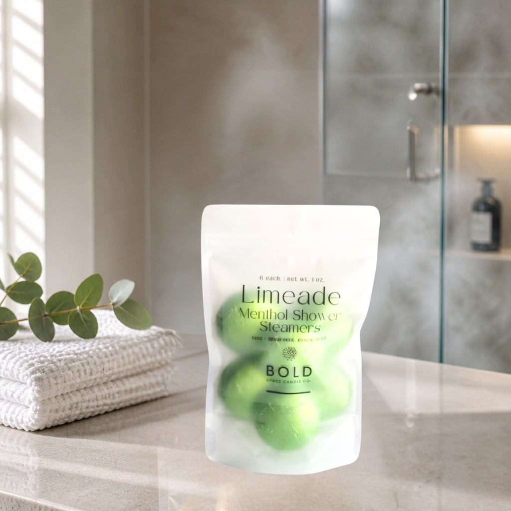 Pack of Limeade Menthol Shower Steamers on a bathroom counter with towels and a plant.