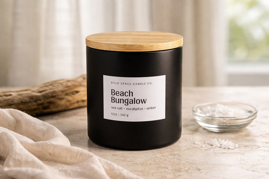 Black candle with a wooden lid labeled 'Beach Bungalow' on a light surface.