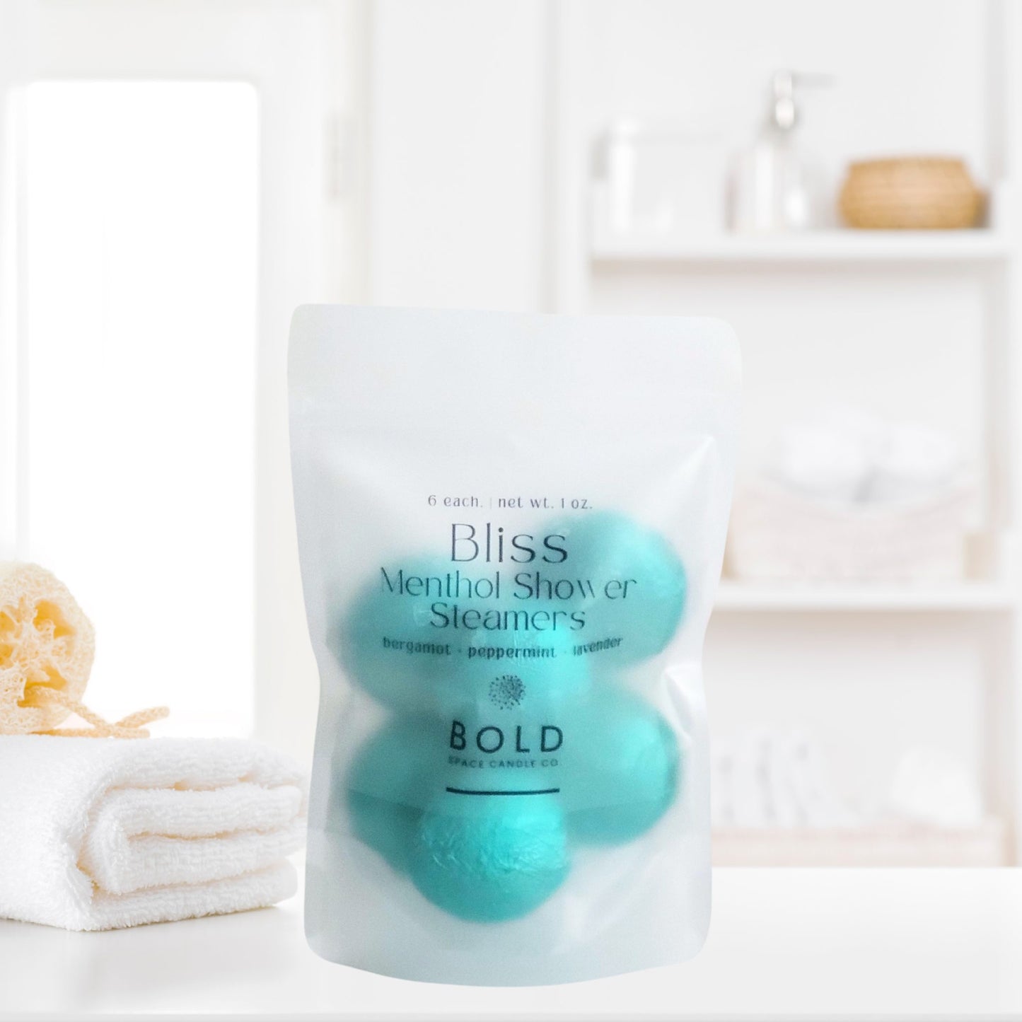 Bliss aromatherapy shower steamers styled beside towels and spa bathroom decor