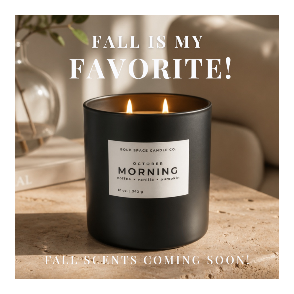 A matte black candle jar with two lit flames sits on a stone surface in a softly lit interior. The front label reads 'BOLD SPACE CANDLE CO.