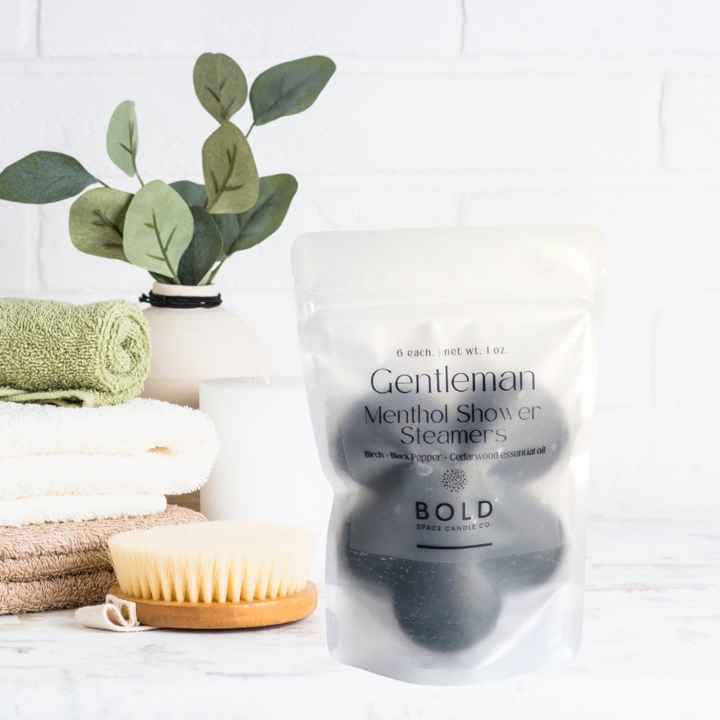 Gentleman - Birch Black Pepper Cedarwood shower steamers in a resealable pouch with towels and a brush in the background.
