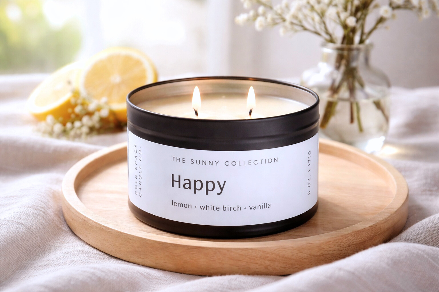 Candle labeled 'Happy' from The Sunny Collection on a wooden tray with a blurred background