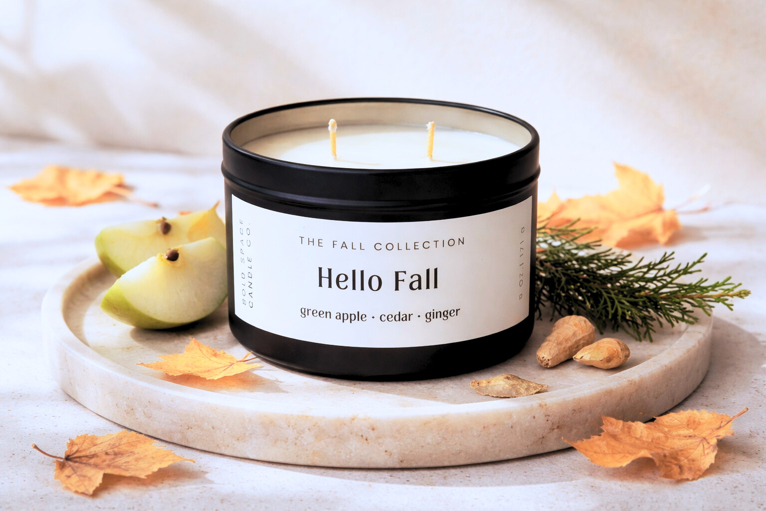 Candle labeled 'Hello Fall' with autumn elements on a white background
