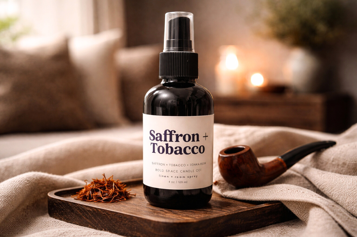 Saffron + Tobacco room spray black glass bottle on a wooden tray with saffron and a pipe in a cozy setting